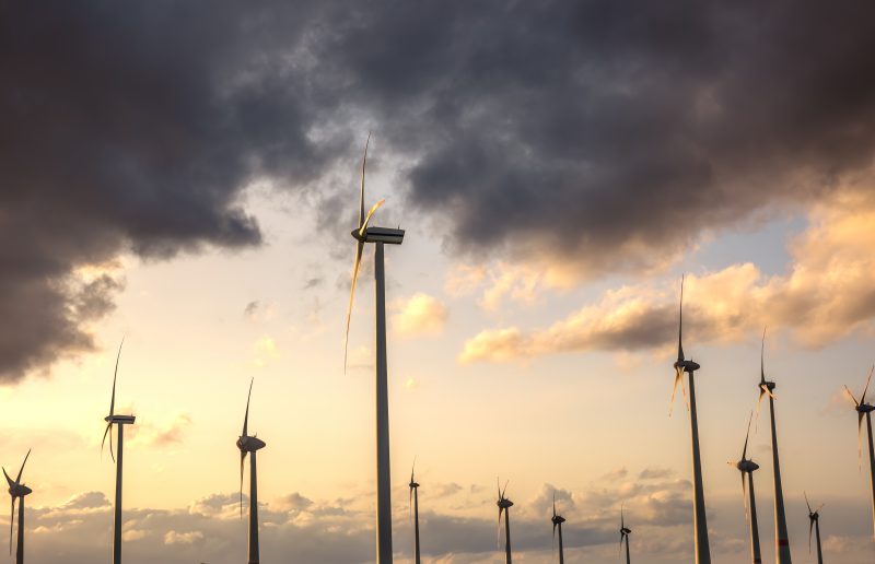 Wind turbines and dramatic clouds. Sunset sky. Renewable energy landscape. About us